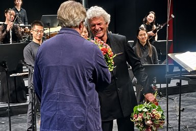 Gratulation für Ulrich Windfuhr Mann bekommt einen Brumenstrauß auf einer Bühne überreicht